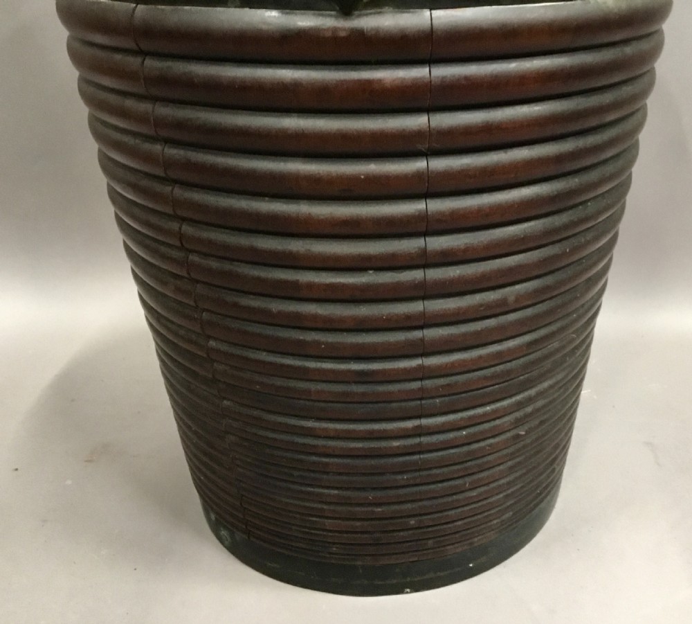 An eighteenth-century mahogany Irish peat bucket featuring a ribbed coopered body, brass banding, and an overhead carrying handle. View VIII