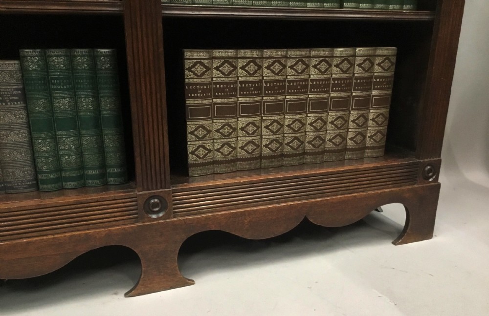 A low Regency mahogany open bookcase featuring two sections with fixed shelving, flanked by fluted pilasters with roundels, set over a shaped apron. View VI