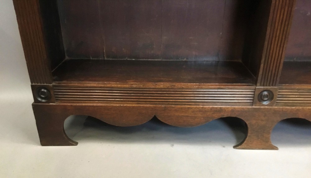 A low Regency mahogany open bookcase featuring two sections with fixed shelving, flanked by fluted pilasters with roundels, set over a shaped apron. View VII