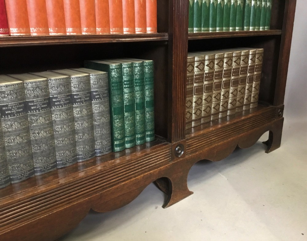 A low Regency mahogany open bookcase featuring two sections with fixed shelving, flanked by fluted pilasters with roundels, set over a shaped apron. View XII