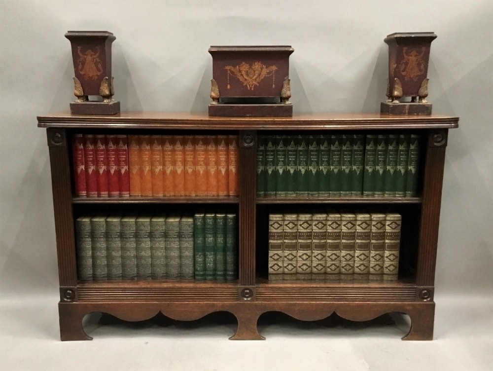 A low Regency mahogany open bookcase featuring two sections with fixed shelving, flanked by fluted pilasters with roundels, set over a shaped apron. View XXII