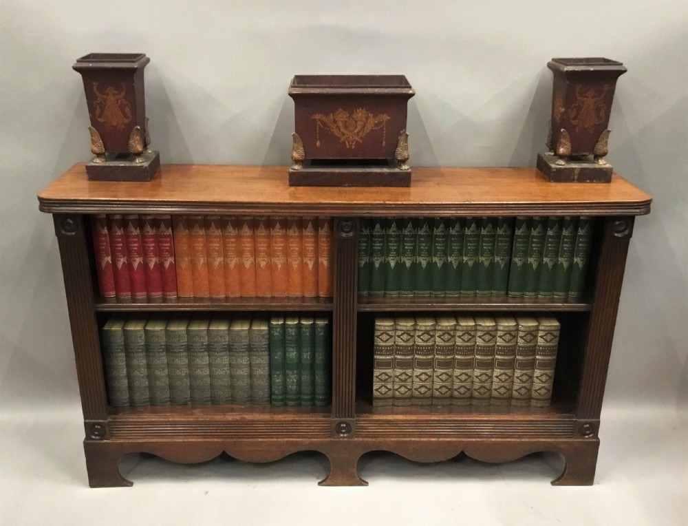 A low Regency mahogany open bookcase featuring two sections with fixed shelving, flanked by fluted pilasters with roundels, set over a shaped apron. View XXIII