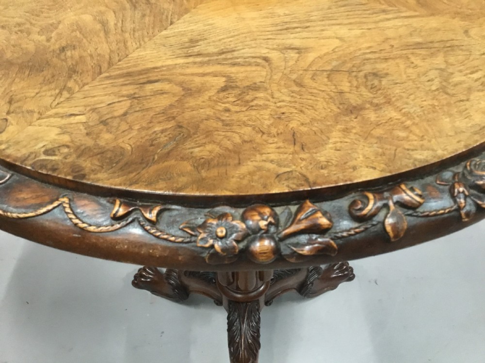 A circular George IV pollard oak occasional table featuring a segmented veneer top, carved rim with floral details, and a tripod pedestal base with carved feet. View VIII