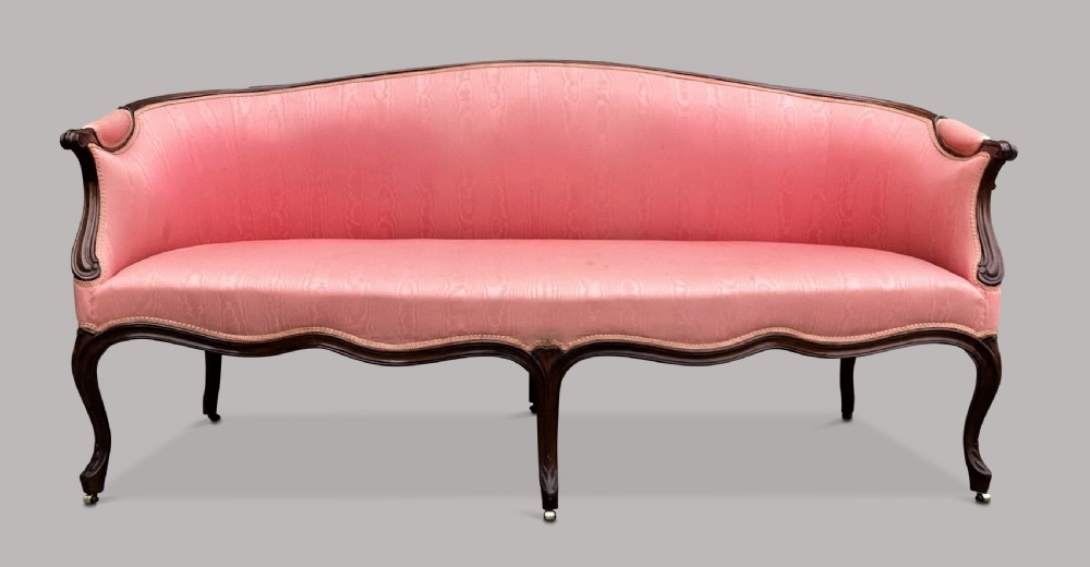 A George III Hepplewhite mahogany settee featuring pink damask upholstery, serpentine backline, and carved cabriole legs on brass castors. View II