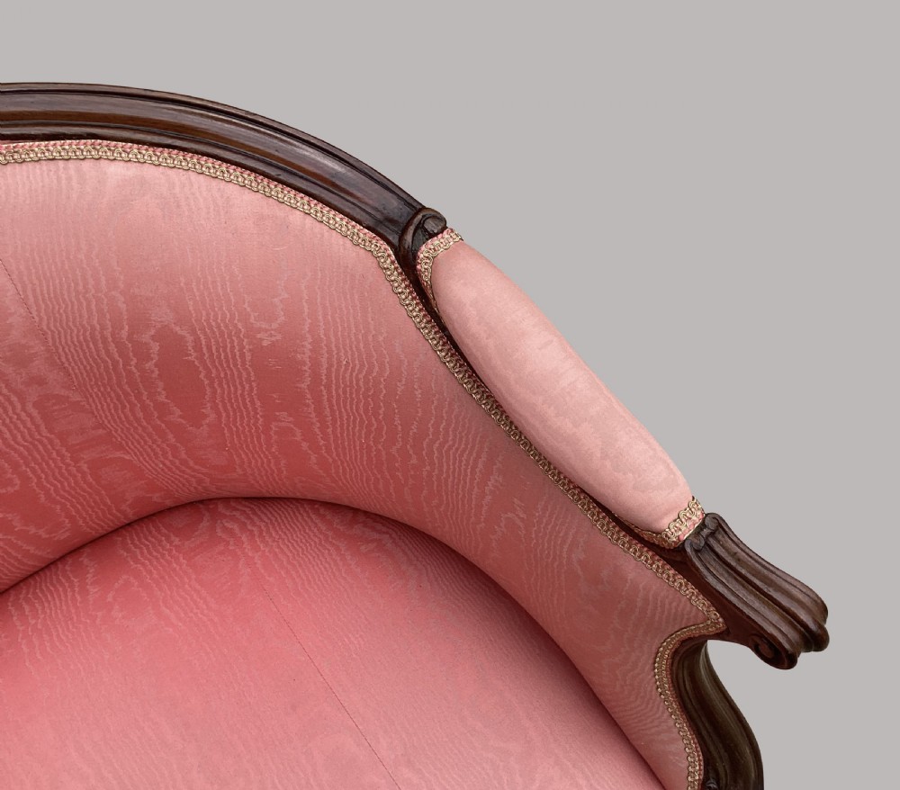 A George III Hepplewhite mahogany settee featuring pink damask upholstery, serpentine backline, and carved cabriole legs on brass castors. View XIV