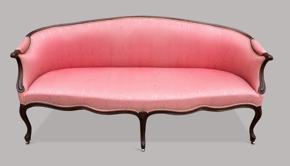 A George III Hepplewhite mahogany settee featuring pink damask upholstery, serpentine backline, and carved cabriole legs on brass castors. View XVI