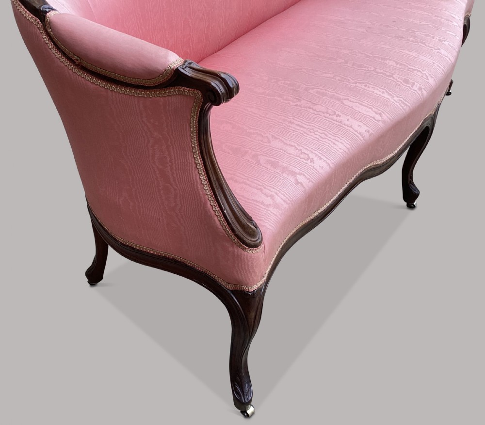 A George III Hepplewhite mahogany settee featuring pink damask upholstery, serpentine backline, and carved cabriole legs on brass castors. View XVII