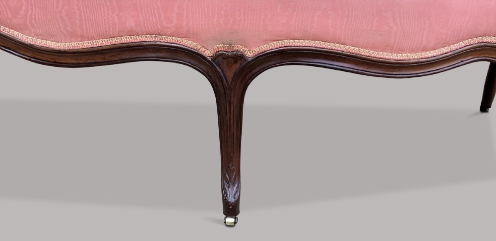 A George III Hepplewhite mahogany settee featuring pink damask upholstery, serpentine backline, and carved cabriole legs on brass castors. View XVIII