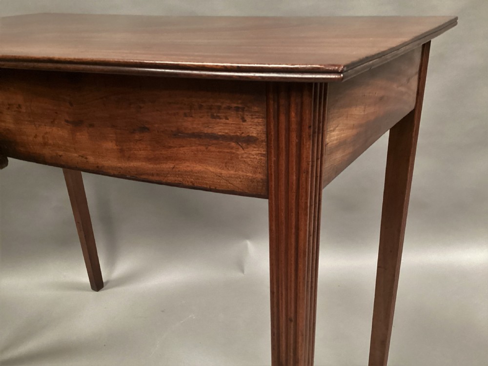 A George III mahogany bow-fronted side table featuring a curved top, frieze panel, and four square tapered legs. View X