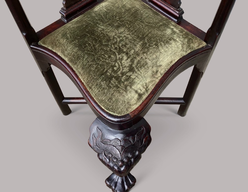An 18th-century Chinese export dark hardwood corner armchair featuring a curved crest rail, carved splats, an olive green velvet seat, and a cabriole front leg with a carved mask and claw foot. View VI