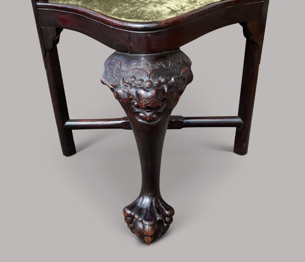 An 18th-century Chinese export dark hardwood corner armchair featuring a curved crest rail, carved splats, an olive green velvet seat, and a cabriole front leg with a carved mask and claw foot. View VII