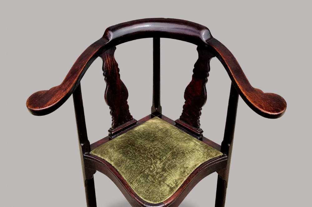 An 18th-century Chinese export dark hardwood corner armchair featuring a curved crest rail, carved splats, an olive green velvet seat, and a cabriole front leg with a carved mask and claw foot. View X