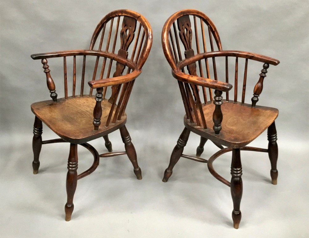 A pair of 19th-century hoop-back Windsor armchairs with pierced central splats, turned legs, curved stretchers, and richly patinated timber.