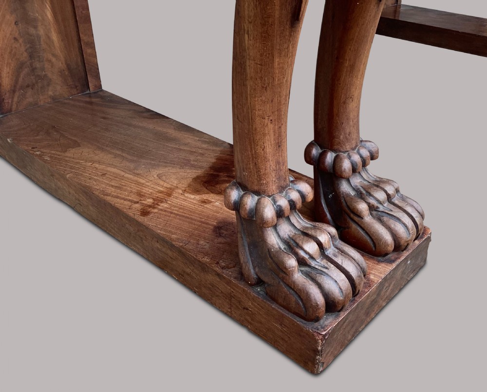 A Regency flame mahogany serving table featuring carved monopodial legs with paw feet and a decorative scrolled cresting rail. View X