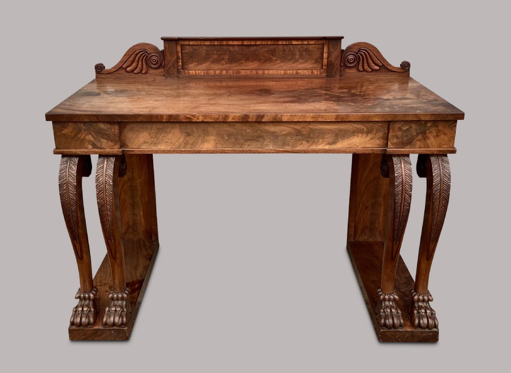 A Regency flame mahogany serving table featuring carved monopodial legs with paw feet and a decorative scrolled cresting rail. View XVI