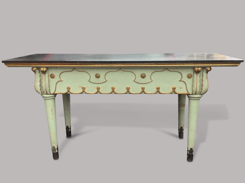 A 19th-century Italian painted side table with a dark top, sage green frame, turned tapering legs, and gilded scalloped apron details.