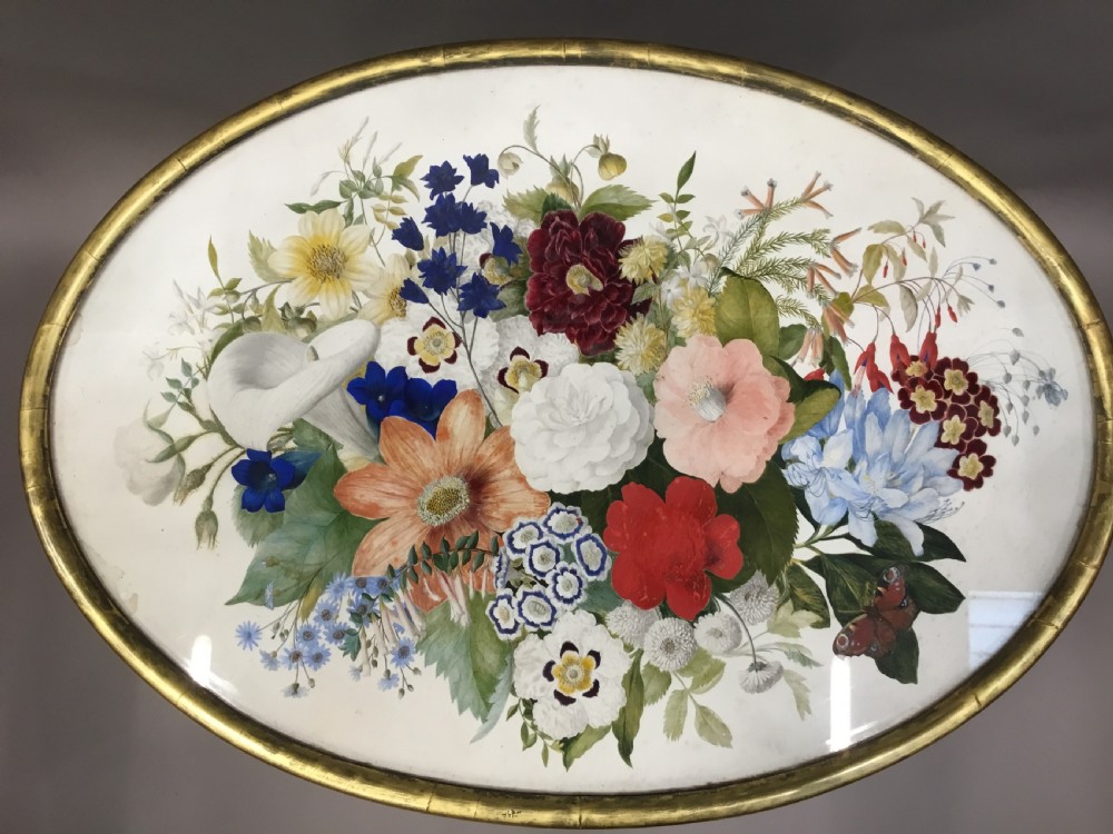 An oval Regency occasional table featuring a hand-painted floral arrangement on the top with a gilt rim, resting on a reeded pedestal stem and carved scroll legs. View IV