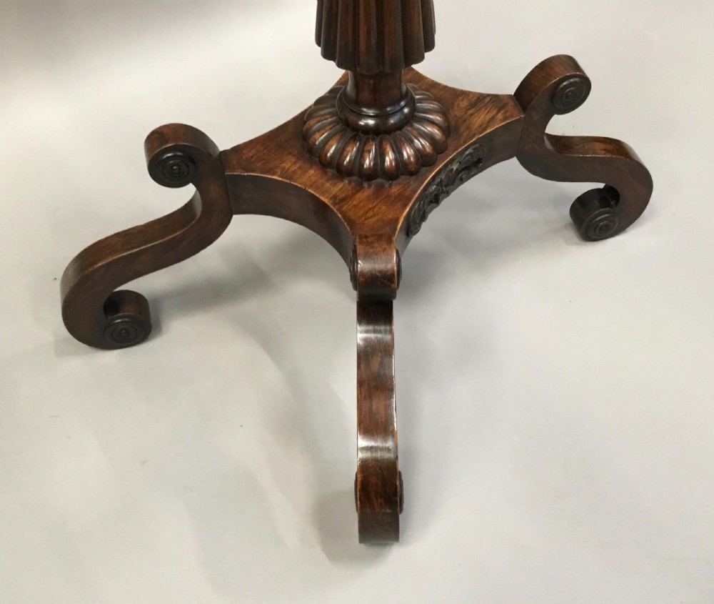 An oval Regency occasional table featuring a hand-painted floral arrangement on the top with a gilt rim, resting on a reeded pedestal stem and carved scroll legs. View VI