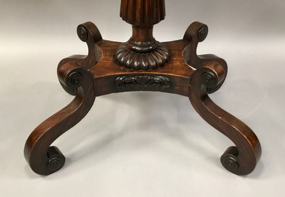 An oval Regency occasional table featuring a hand-painted floral arrangement on the top with a gilt rim, resting on a reeded pedestal stem and carved scroll legs. View VIII