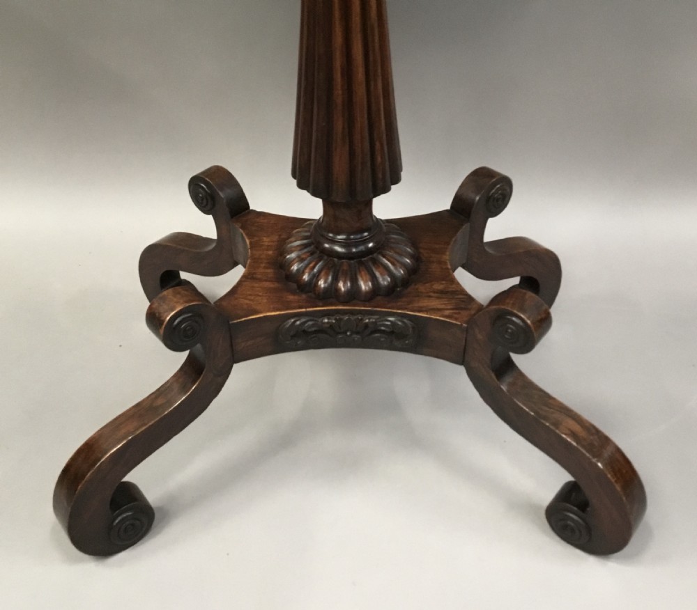 An oval Regency occasional table featuring a hand-painted floral arrangement on the top with a gilt rim, resting on a reeded pedestal stem and carved scroll legs. View X