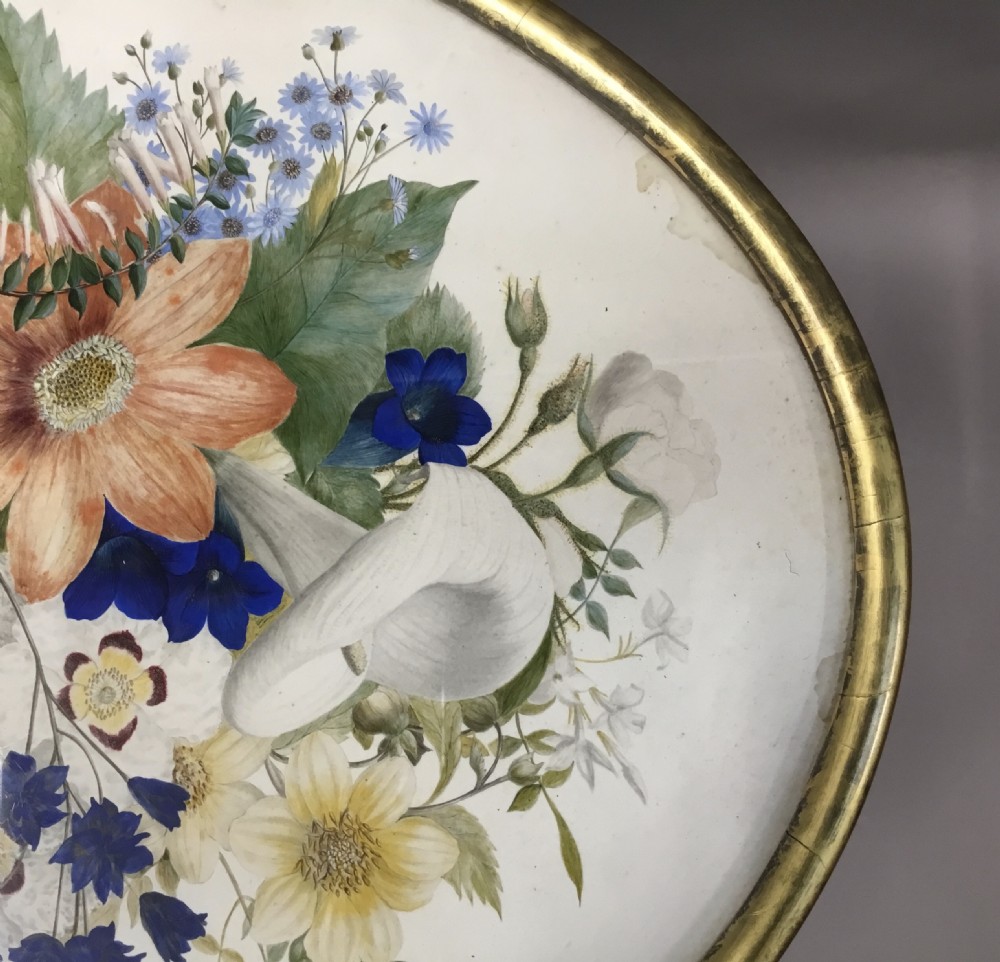 An oval Regency occasional table featuring a hand-painted floral arrangement on the top with a gilt rim, resting on a reeded pedestal stem and carved scroll legs. View XI