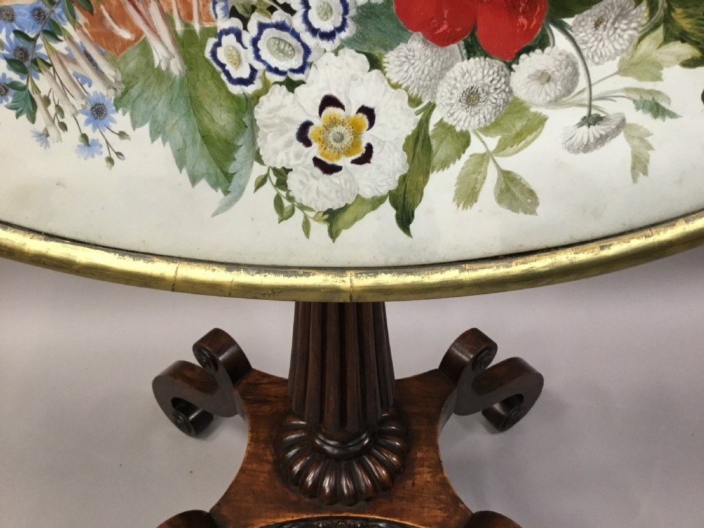 An oval Regency occasional table featuring a hand-painted floral arrangement on the top with a gilt rim, resting on a reeded pedestal stem and carved scroll legs. View XIII