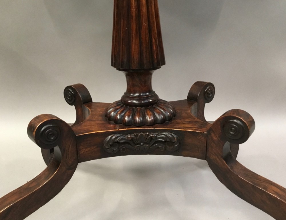 An oval Regency occasional table featuring a hand-painted floral arrangement on the top with a gilt rim, resting on a reeded pedestal stem and carved scroll legs. View XVIII