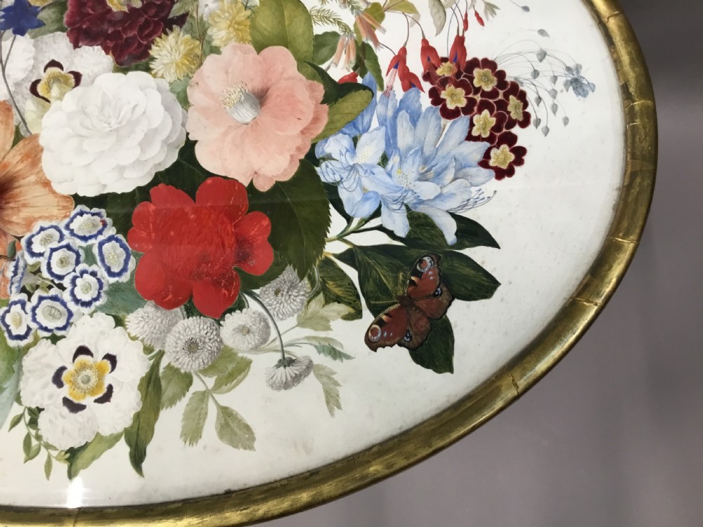 An oval Regency occasional table featuring a hand-painted floral arrangement on the top with a gilt rim, resting on a reeded pedestal stem and carved scroll legs. View XXIII