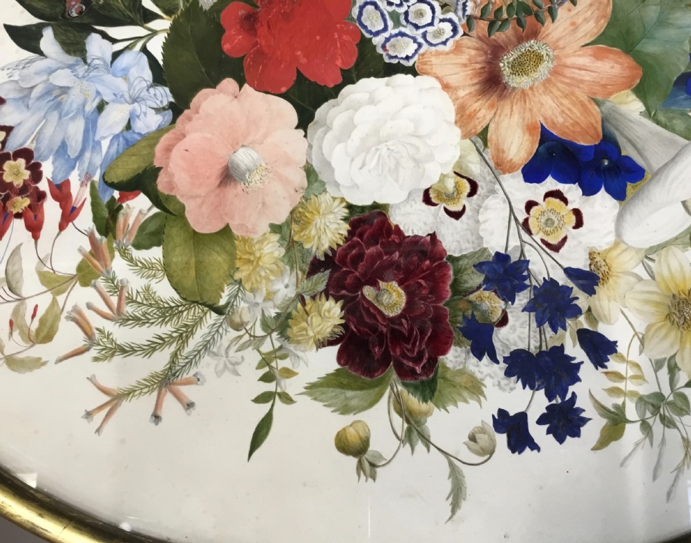 An oval Regency occasional table featuring a hand-painted floral arrangement on the top with a gilt rim, resting on a reeded pedestal stem and carved scroll legs. View XXVI