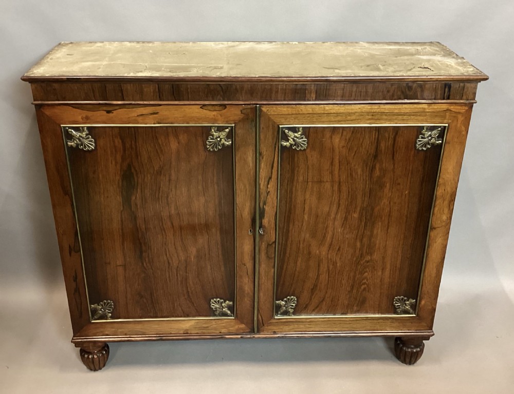 A Regency rosewood side cabinet featuring two panelled doors with brass corner mounts, set beneath a white marble top. View XIII