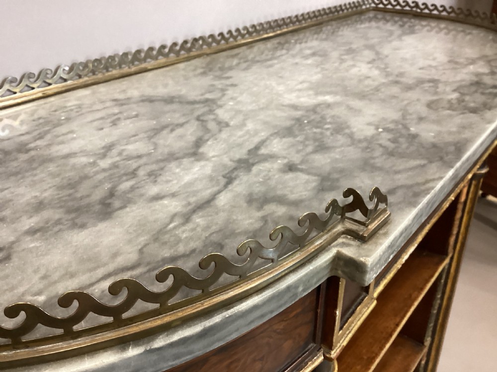 A Regency rosewood breakfront open cabinet featuring a marble top with a brass gallery, central open shelves flanked by faux leather book spines, and fluted gilt columns on tapered legs. View VI