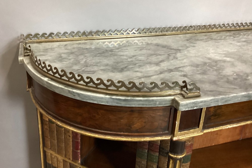 A Regency rosewood breakfront open cabinet featuring a marble top with a brass gallery, central open shelves flanked by faux leather book spines, and fluted gilt columns on tapered legs. View VII