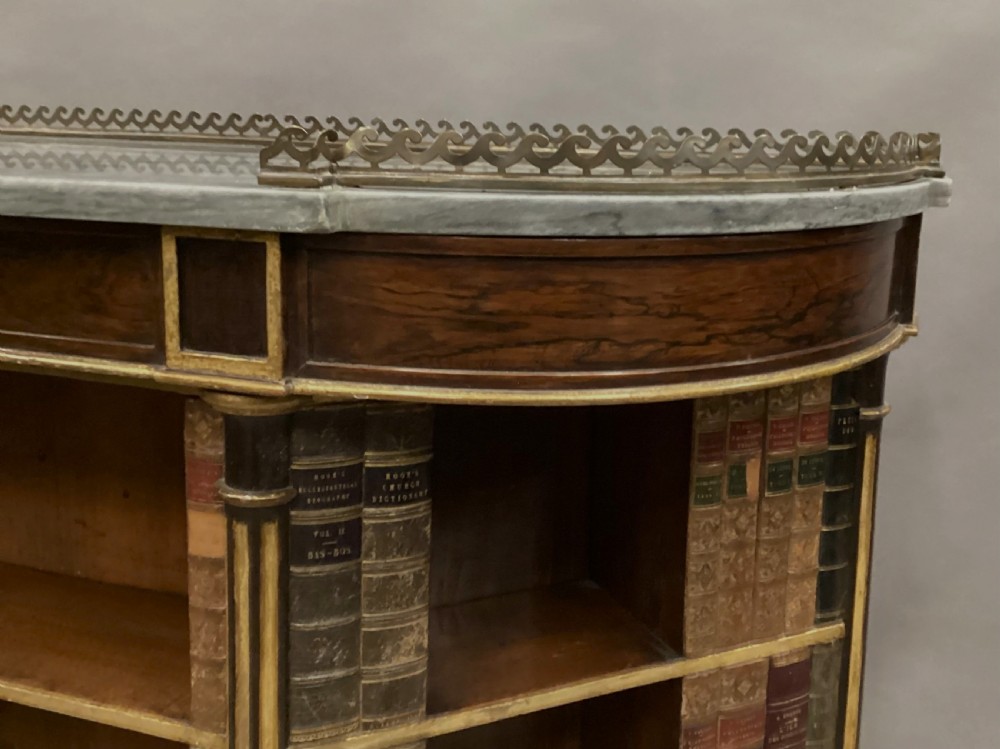 A Regency rosewood breakfront open cabinet featuring a marble top with a brass gallery, central open shelves flanked by faux leather book spines, and fluted gilt columns on tapered legs. View X