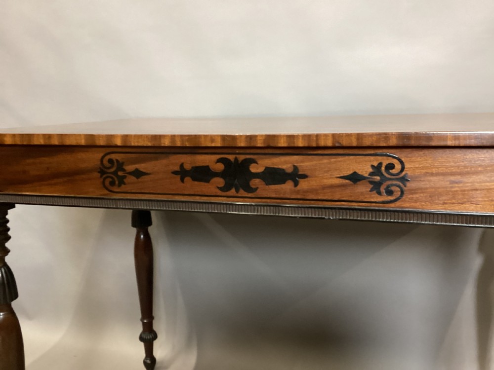 A Regency mahogany side table featuring ebony inlaid geometric scrollwork on the frieze and four reeded turned legs. View IV