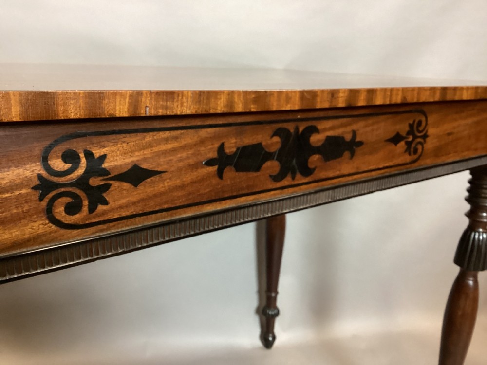 A Regency mahogany side table featuring ebony inlaid geometric scrollwork on the frieze and four reeded turned legs. View VI