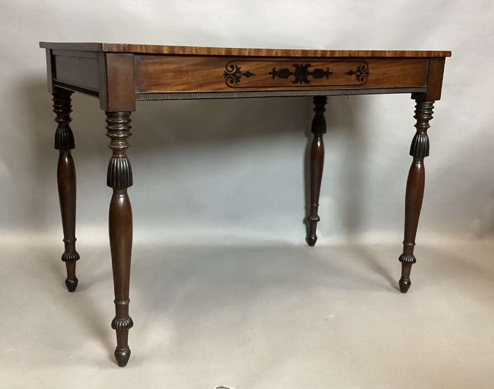 A Regency mahogany side table featuring ebony inlaid geometric scrollwork on the frieze and four reeded turned legs. View XII