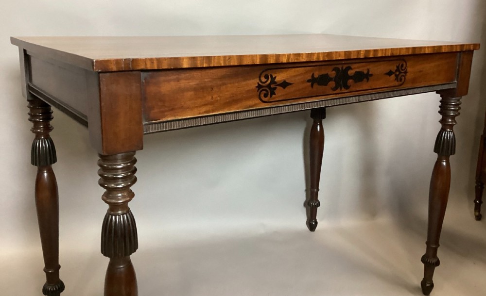 A Regency mahogany side table featuring ebony inlaid geometric scrollwork on the frieze and four reeded turned legs. View XIII