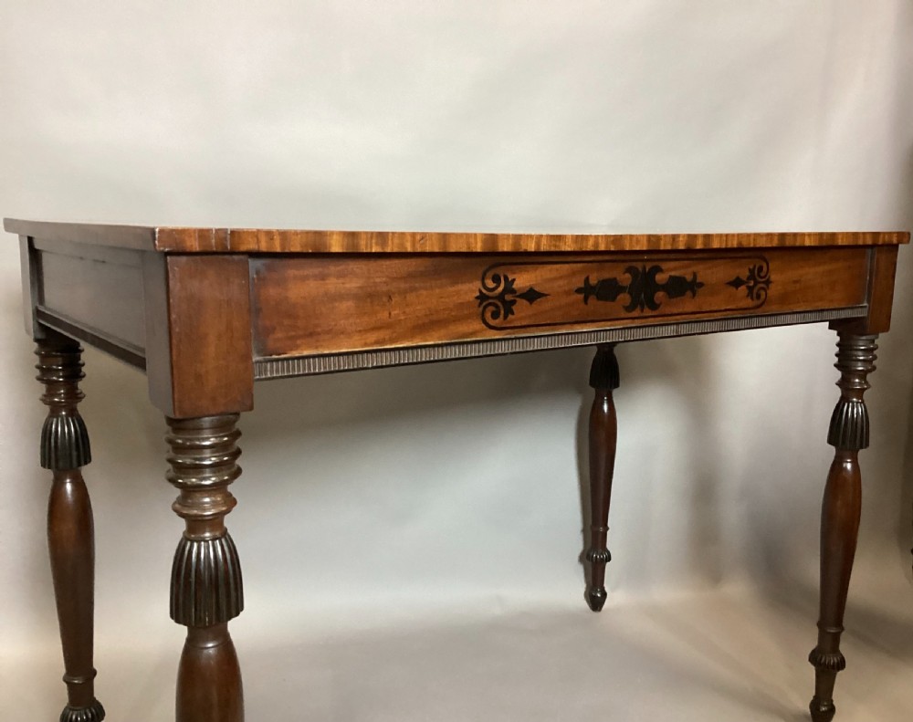 A Regency mahogany side table featuring ebony inlaid geometric scrollwork on the frieze and four reeded turned legs. View XV