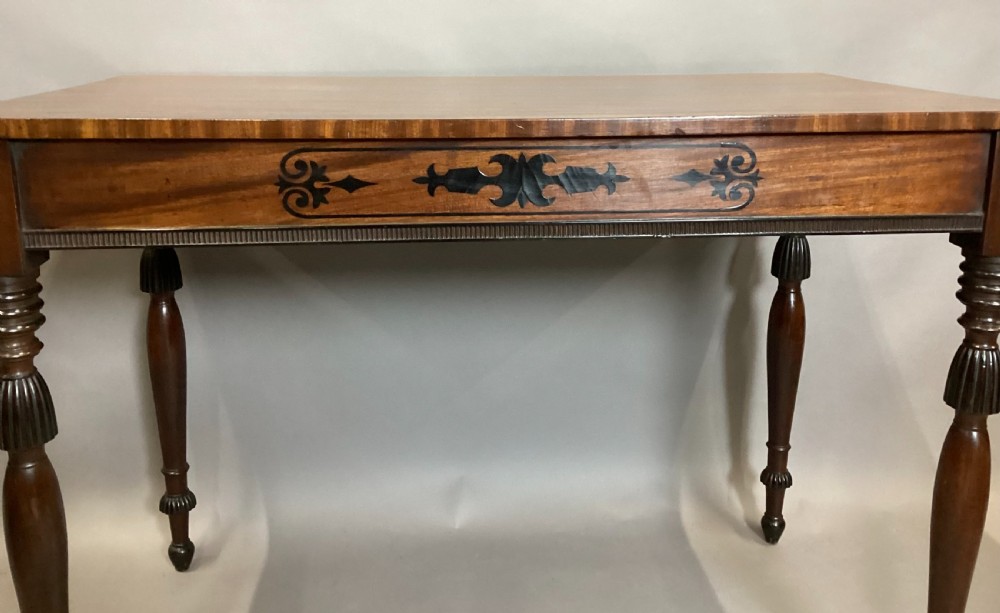 A Regency mahogany side table featuring ebony inlaid geometric scrollwork on the frieze and four reeded turned legs. View XVII