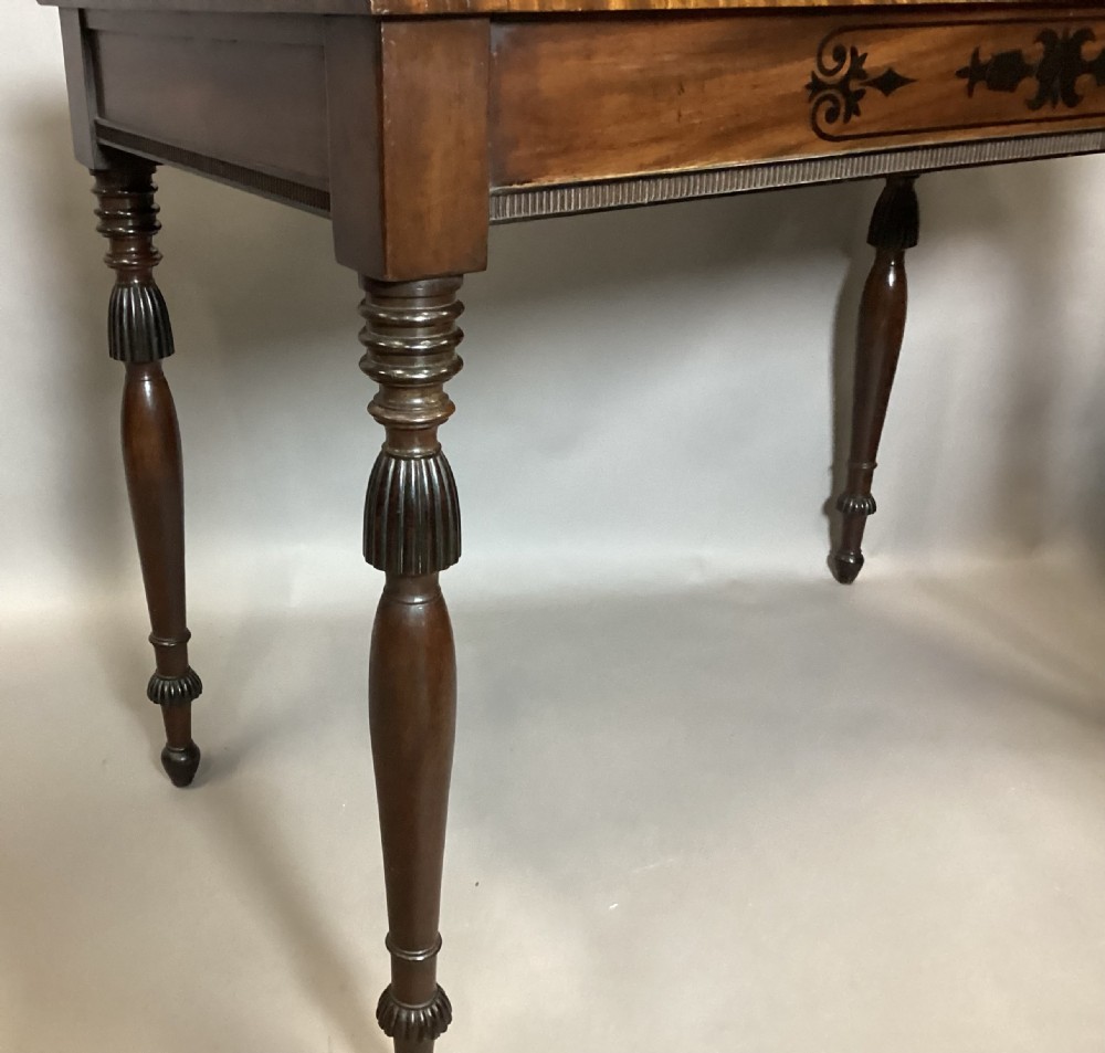 A Regency mahogany side table featuring ebony inlaid geometric scrollwork on the frieze and four reeded turned legs. View XX