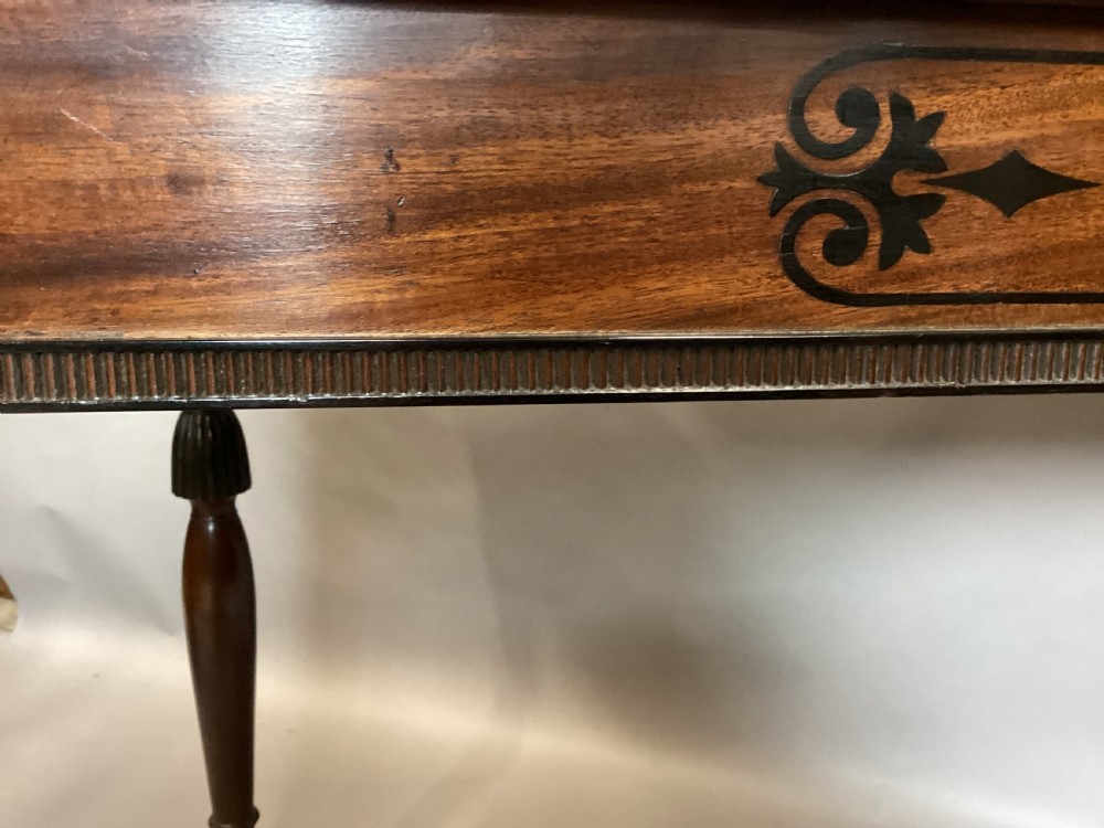 A Regency mahogany side table featuring ebony inlaid geometric scrollwork on the frieze and four reeded turned legs. View XXIII