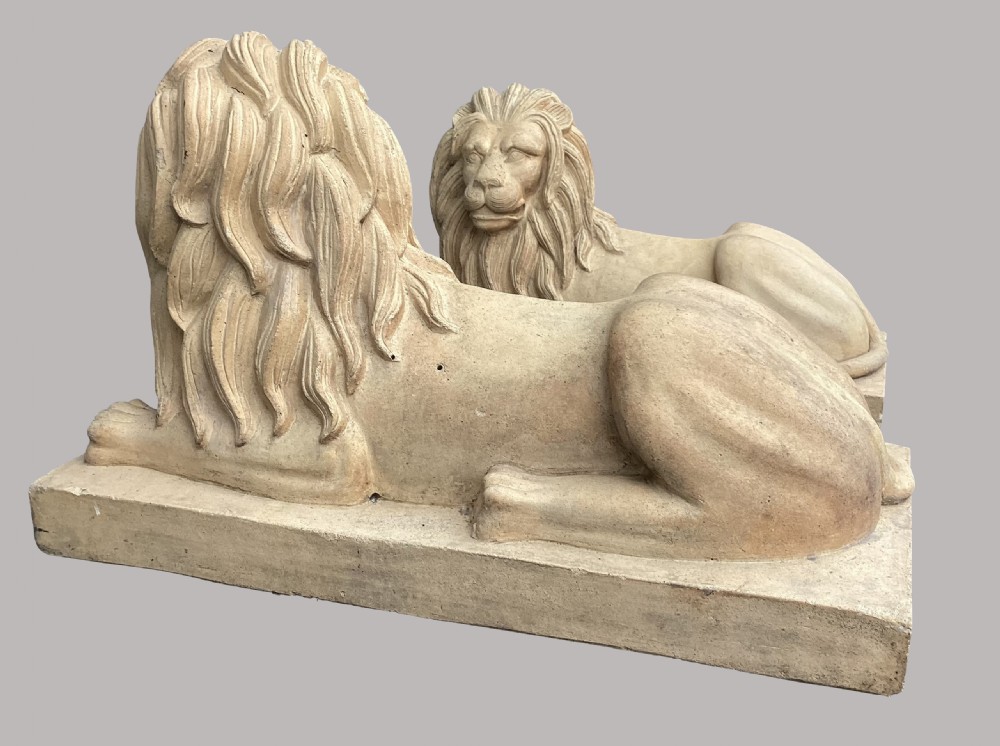 A pair of large nineteenth-century buff terracotta lions depicted in a recumbent position on rectangular bases. View VI