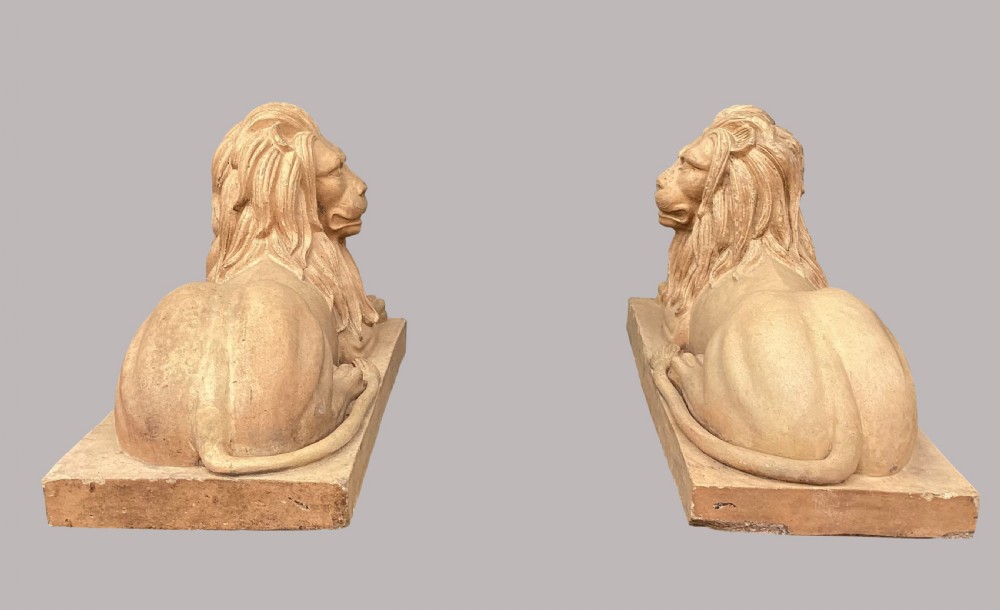 A pair of large nineteenth-century buff terracotta lions depicted in a recumbent position on rectangular bases. View XV