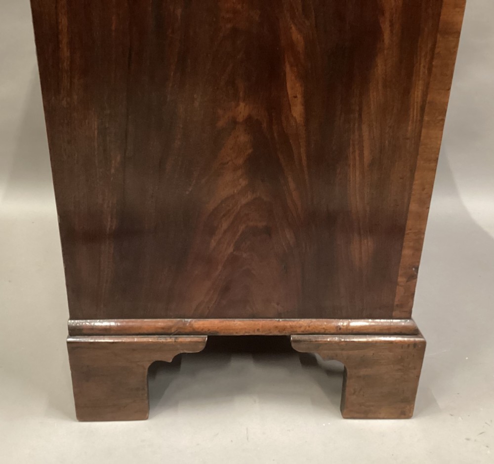 A compact Regency chest of drawers crafted from figured mahogany timber featuring four cockbeaded drawers, brass circular knobs, and traditional bracket feet. View X