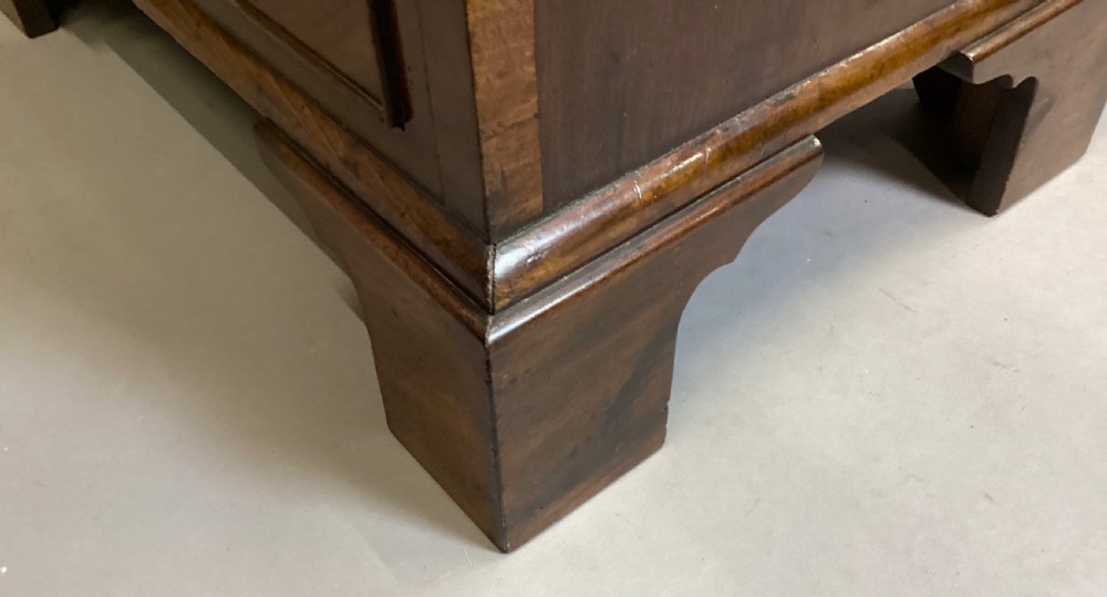 A compact Regency chest of drawers crafted from figured mahogany timber featuring four cockbeaded drawers, brass circular knobs, and traditional bracket feet. View XVII