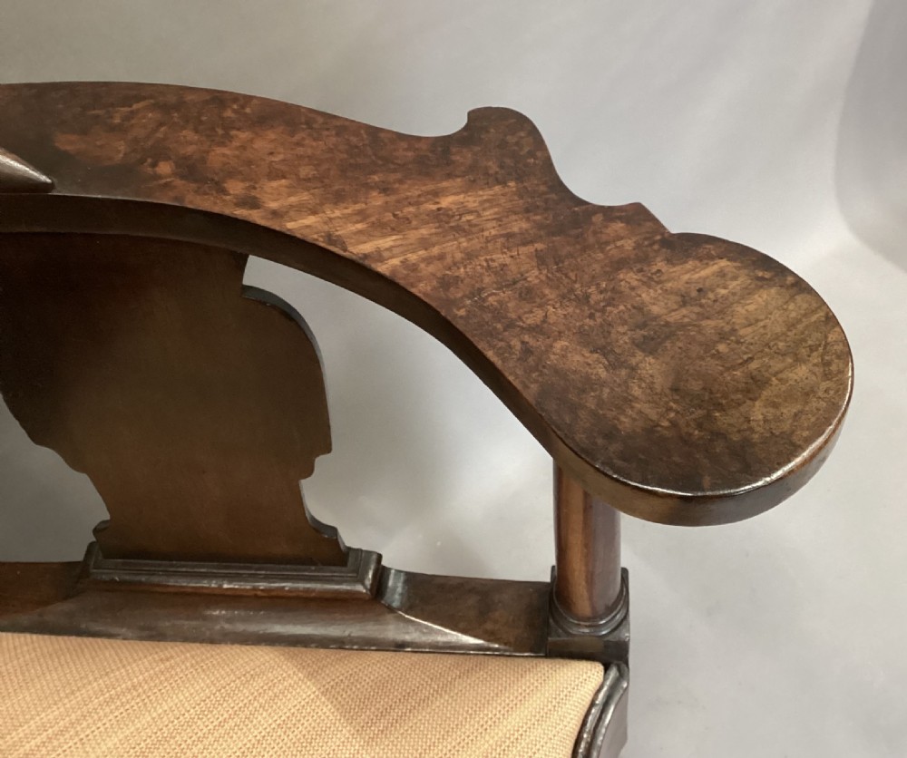 An antique George I walnut corner chair featuring a curved backrest, turned support posts, twin splats, a drop-in seat, and a central cabriole front leg. View V