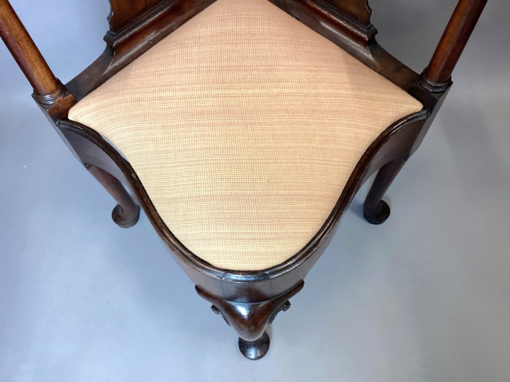 An antique George I walnut corner chair featuring a curved backrest, turned support posts, twin splats, a drop-in seat, and a central cabriole front leg. View XVIII