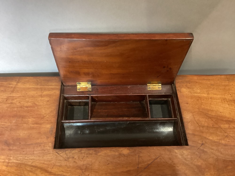 A Regency mahogany chamber writing table featuring an ebony-banded drawer front, reeded turned legs, and brass castors. View IV