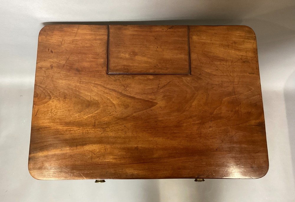 A Regency mahogany chamber writing table featuring an ebony-banded drawer front, reeded turned legs, and brass castors. View XVII