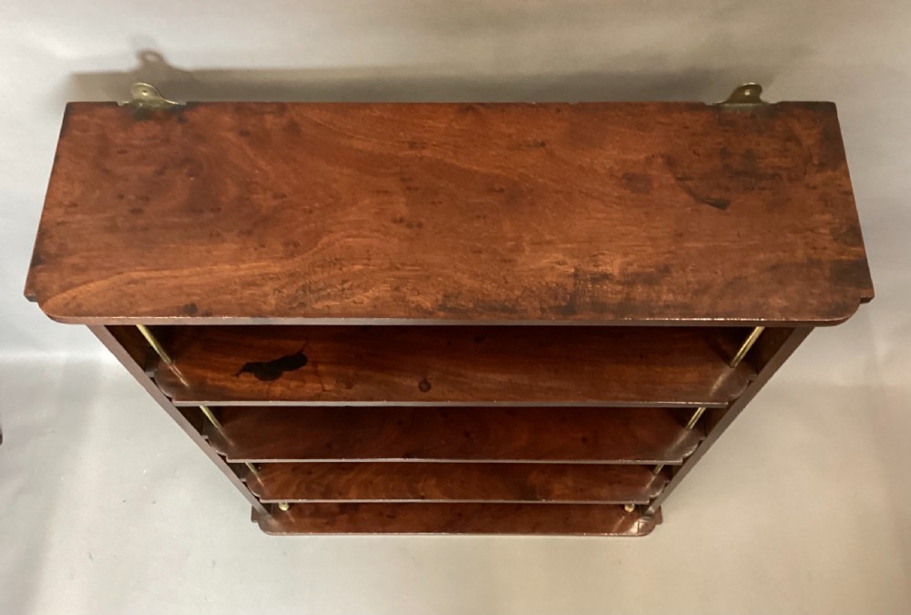 A four-tier Regency mahogany wall shelf unit featuring vertical brass support rods and top brass mounting brackets. View VII